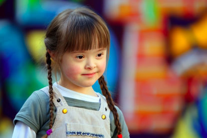 downs syndrome child with playground in background