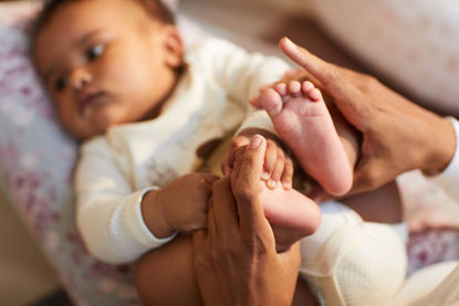infant with adult holding feet