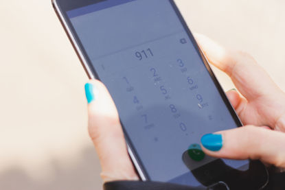 person holding smartphone with numbers 911 on screen