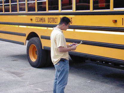 man inspecting bus with clipboard